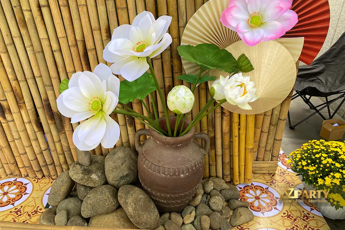 Tiểu cảnh trang trí Tết với bình gốm nâu cắm hoa sen trắng và hồng đặt trên nền đá cuội