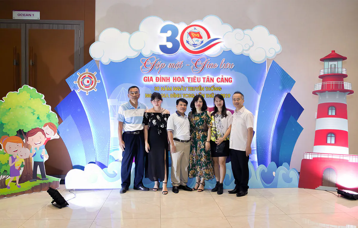 Nhóm cán bộ nhân viên chụp ảnh lưu niệm trước backdrop ngày hội gia đình Hoa Tiêu Tân Cảng 30 năm truyền thống