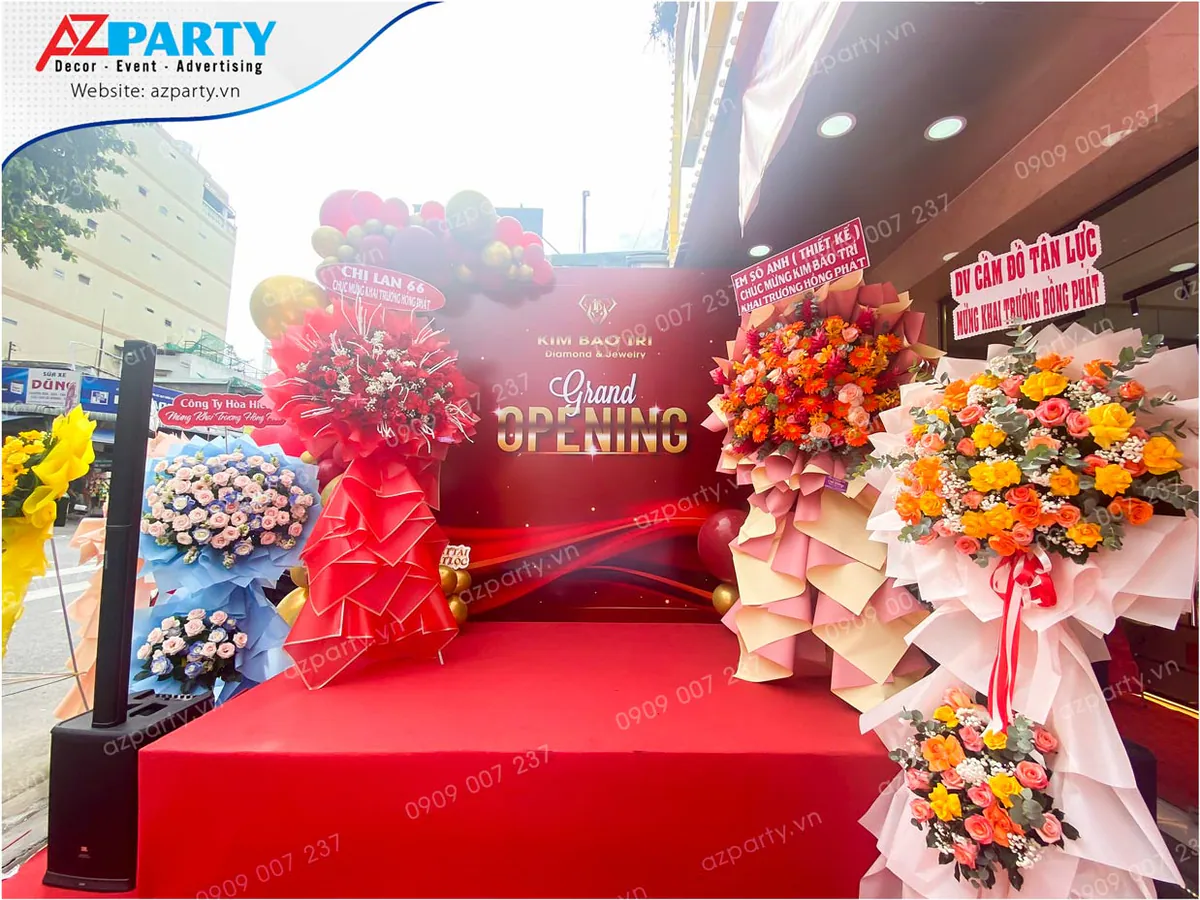 Sân khấu backdrop Grand Opening của tiệm vàng Kim Bảo Trí trang trí hoa tươi sang trọng