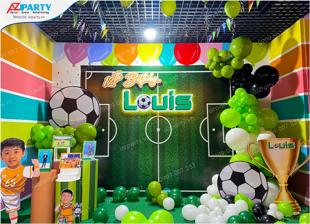 Trang trí tiệc sinh nhật chủ đề bóng đá cho bé Louis tròn 12 tuổi với backdrop in hình sân bóng, mô hình cúp vàng vô địch, hình chibi bé Louis dễ thương cùng bong bóng tone màu xanh lá cây, trắng và đen.