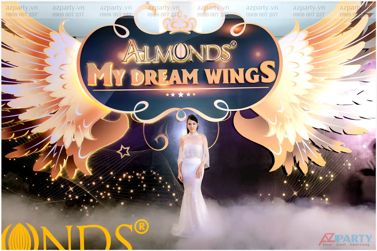 Đại diện thương hiệu Almonds sang trọng chụp hình tại backdrop 'My Dream Wings' thiết kế đôi cánh vàng kim ấn tượng.