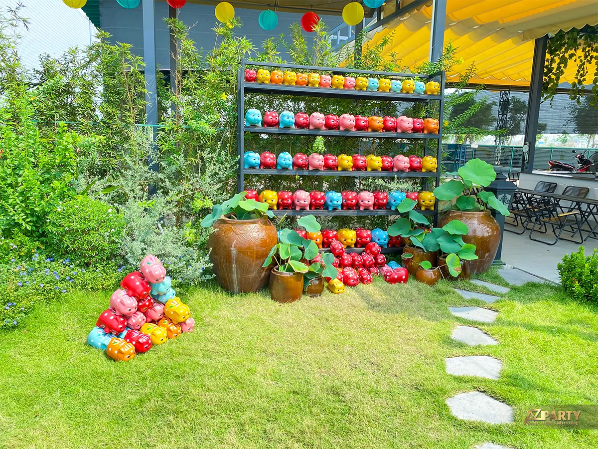 Kệ heo đất nhiều màu bên chum sành và cây xanh trong vườn Tết An Huy