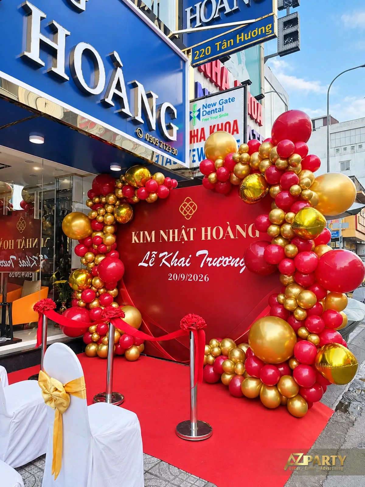Góc nghiêng backdrop đỏ Kim Nhật Hoàng với cụm bóng vàng và trụ băng phía trước