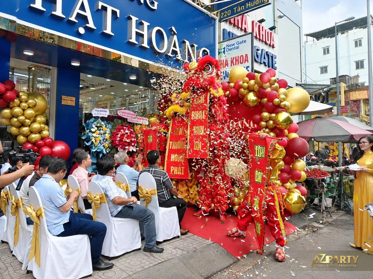 Đội lân biểu diễn với liễn chúc mừng và giấy kim tuyến trước tiệm vàng