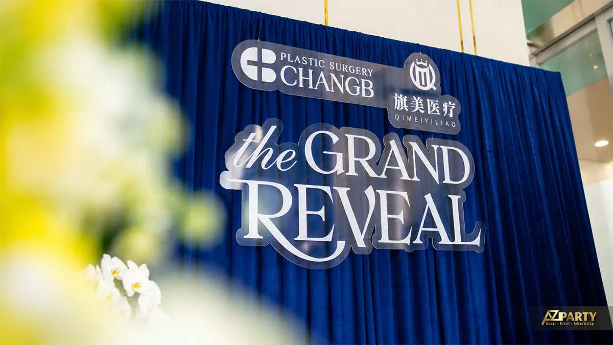 Chữ The Grand Reveal và logo ChangB trên nền rèm xanh