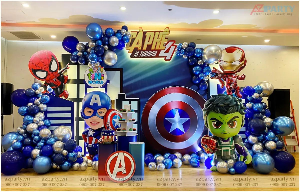 Sân khấu trang trí tiệc sinh nhật 4 tuổi của bé Cà Phê chủ đề Avengers với backdrop hoành tráng, bong bóng màu xanh dương, bạc metallic và standee Hulk, Người Nhện, Iron Man.
