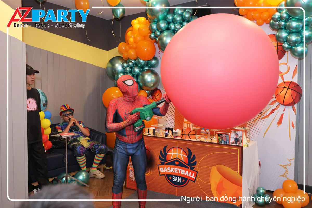 Nghệ sĩ hóa trang thành người nhện Spider-Man đang biểu diễn bơm quả bóng bay khổng lồ màu đỏ tại tiệc sinh nhật bé Sam.