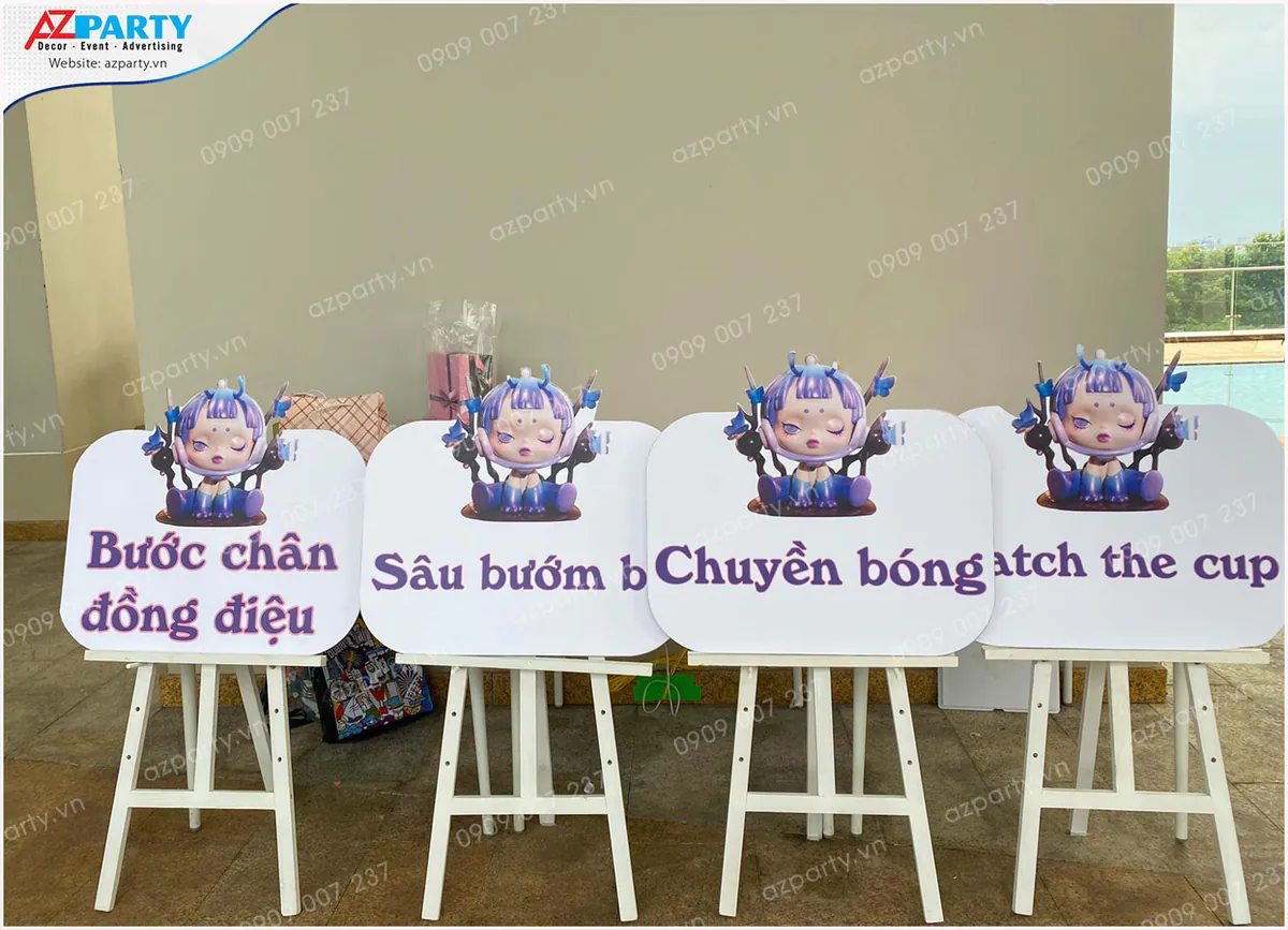 Bảng thông tin các trò chơi hoạt náo ngoài trời được đặt trên giá đỡ gỗ sơn trắng in hình Skullpanda xinh xắn.