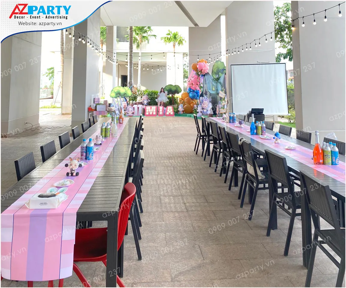 Không gian set up hai dãy bàn tiệc dài ngoài trời có trải khăn runner sọc hồng tím ngọt ngào chuẩn bị đón khách.