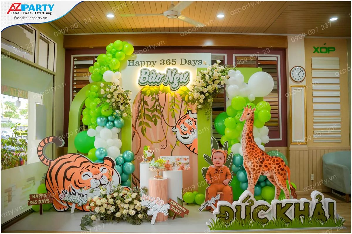 Sân khấu trang trí tiệc thôi nôi chủ đề muông thú rừng xanh Safari cho bé Bảo Ngư (Đức Khải) có mô hình chú hổ con và chú hươu cao cổ đáng yêu.