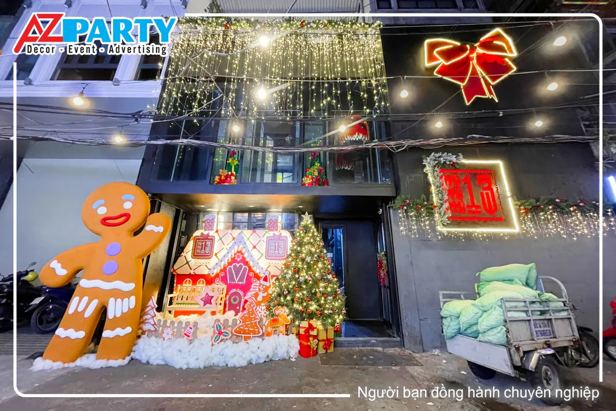 Tiểu cảnh noel tại khu 13 Club. Được trang trí theo concept ngôi nhà bánh gừng, nổi bật là hình ảnh cậu bé bánh gừng khổng lồ đứng vẫy tay chào, bên cạnh là ngôi nhà bánh gừng cùng cây thông noel. Cửa kính được treo những dây đèn led vàng lấp lánh, phần tưởng còn lại được treo 1 chiếc nơ đỏ có đèn neon bao quanh, bên dưới là logo của khu 13 club 