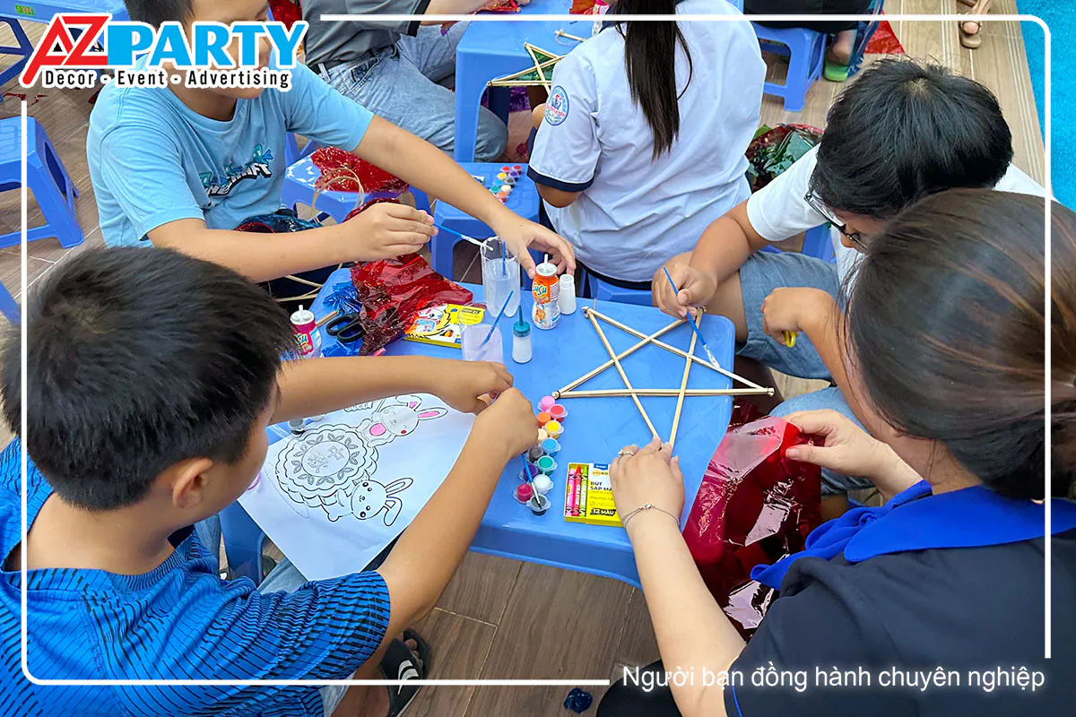 Các em nhỏ cùng nhau hào hứng làm và trang trí lồng đèn trung thu bằng giấy kiếng đỏ.