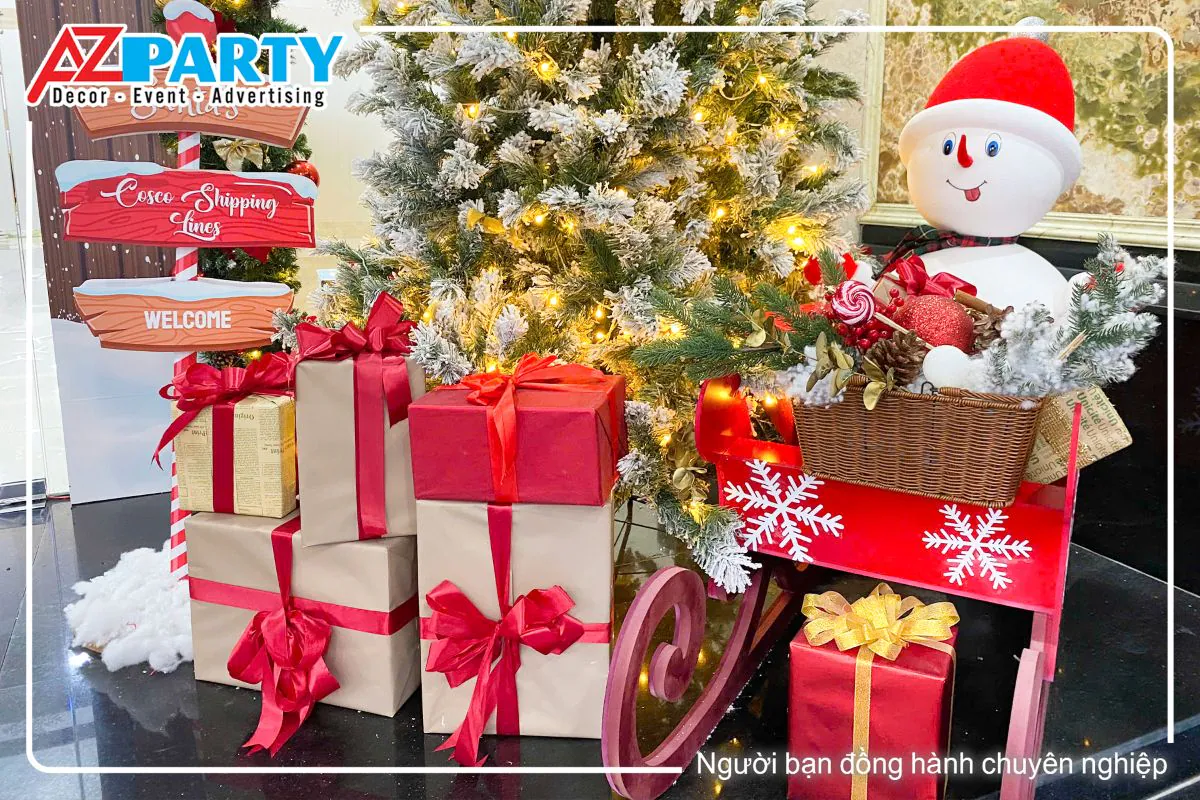 chú người tuyết ngồi trên xe trượt, bên cạnh là những hộp quà