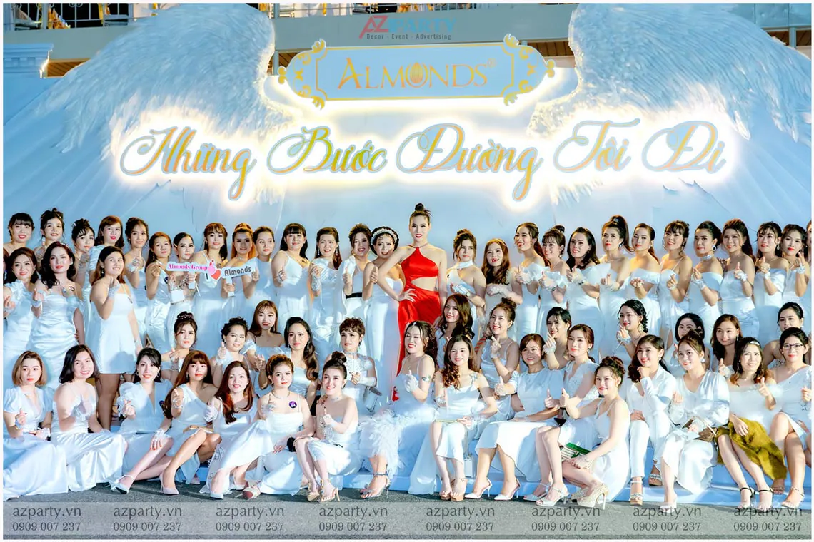 Đại gia đình mỹ phẩm Almonds diện đầm trắng đồng điệu check-in trước backdrop đôi cánh thiên thần lộng lẫy.
