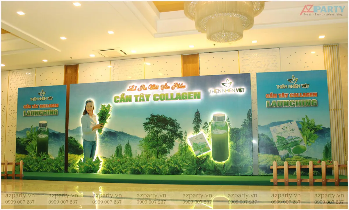 Toàn cảnh sân khấu và khu vực backdrop sự kiện ra mắt sản phẩm Cần Tây Collagen Thiên Nhiên Việt được trang trí hàng rào gỗ mộc mạc.