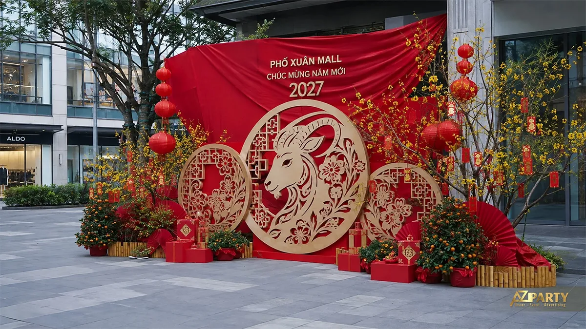 Không gian Tết ngoài trời tại Phố Xuân Mall với phông đỏ, cụm hoa tròn, cây mai và quà Tết