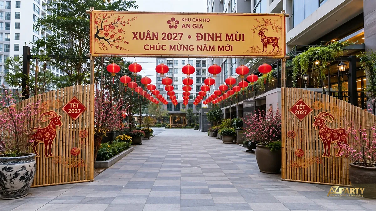 Cổng khu căn hộ An Gia bằng tre với biển chào Xuân 2027, dãy đèn lồng đỏ và hoa đào