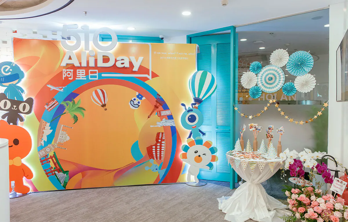 Không gian trang trí sự kiện 510 AliDay với backdrop rực rỡ sắc màu chủ đề du lịch và góc bàn trang trí xinh xắn.