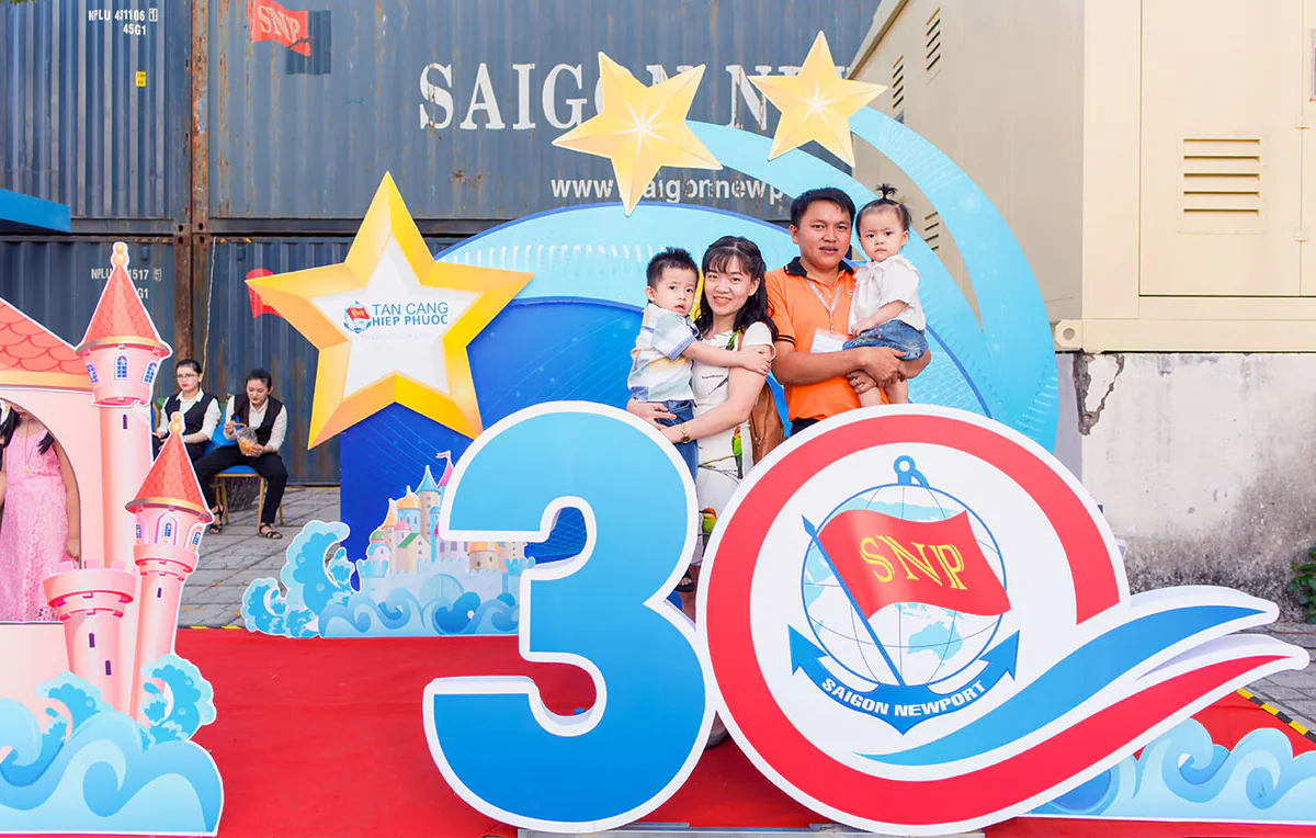 Một gia đình trẻ khác gồm bố mẹ và hai con nhỏ check-in vui vẻ tại khu vực tiểu cảnh số 30 và logo SNP của Ngày hội gia đình Tân Cảng Sài Gòn Hiệp Phước.