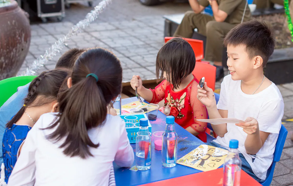 Các em thiếu nhi vui vẻ tụ tập tại bàn làm tranh cát, tự tay sáng tạo những bức tranh nhiều màu sắc sinh động trong ngày hội.