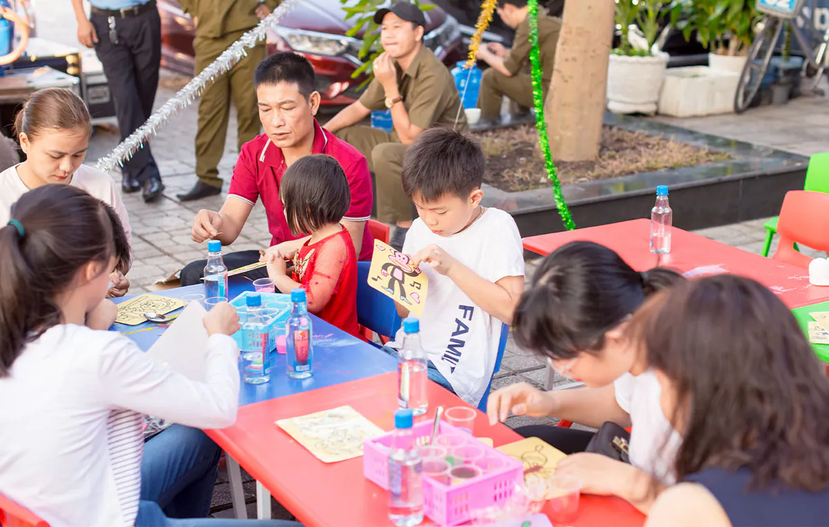 Một góc khác của khu vực trò chơi tranh cát, các bậc phụ huynh đang đồng hành và hướng dẫn con em mình hoàn thành bức tranh sinh động.