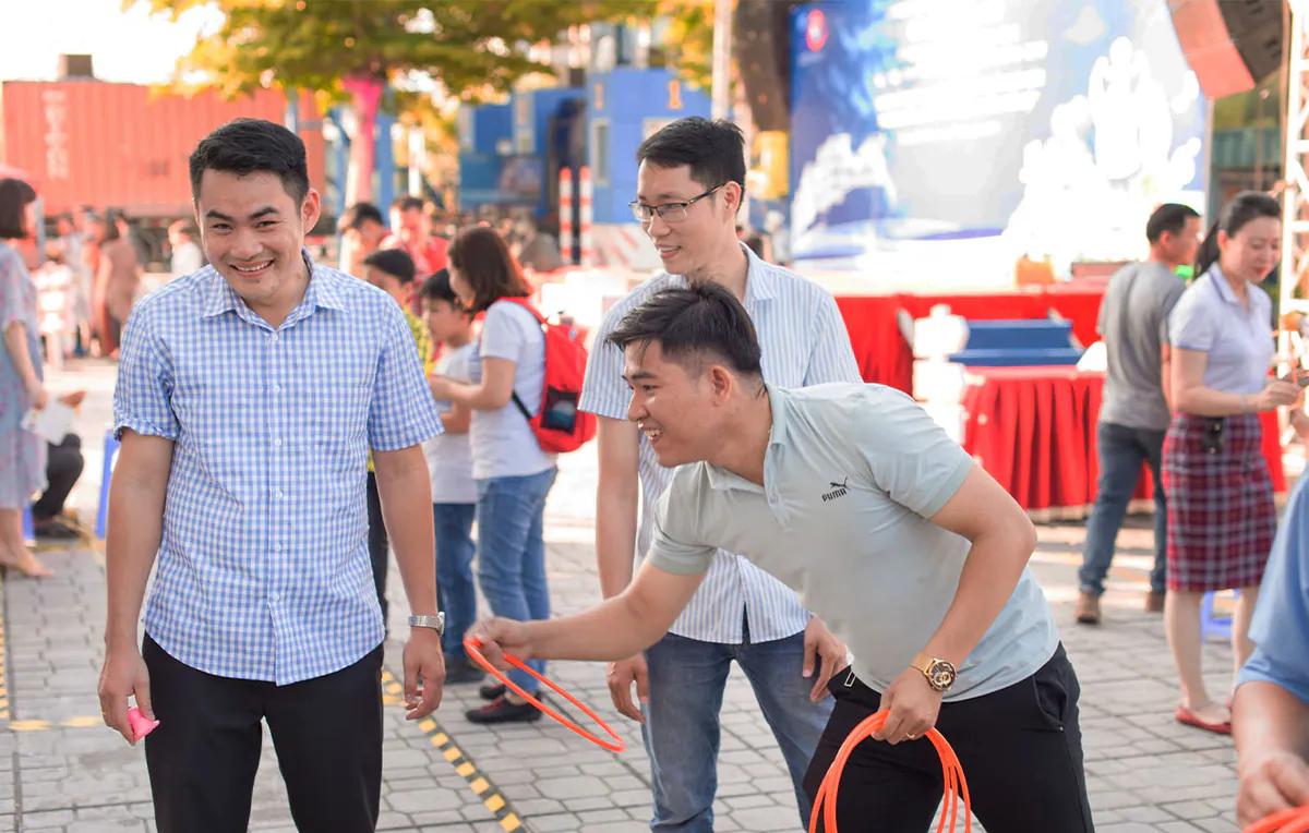 Các nam nhân viên văn phòng tham gia trò chơi ném vòng cổ chai đầy thử thách và kịch tính tại sự kiện Ngày hội gia đình.