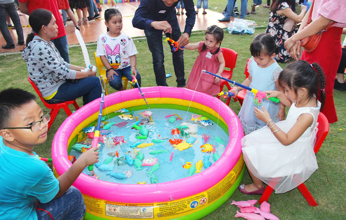 Các em nhỏ hào hứng tham gia trò chơi câu cá nhựa tại bể phao mini nhiều màu sắc trên bãi cỏ trong ngày hội gia đình Tân Cảng Sài Gòn.