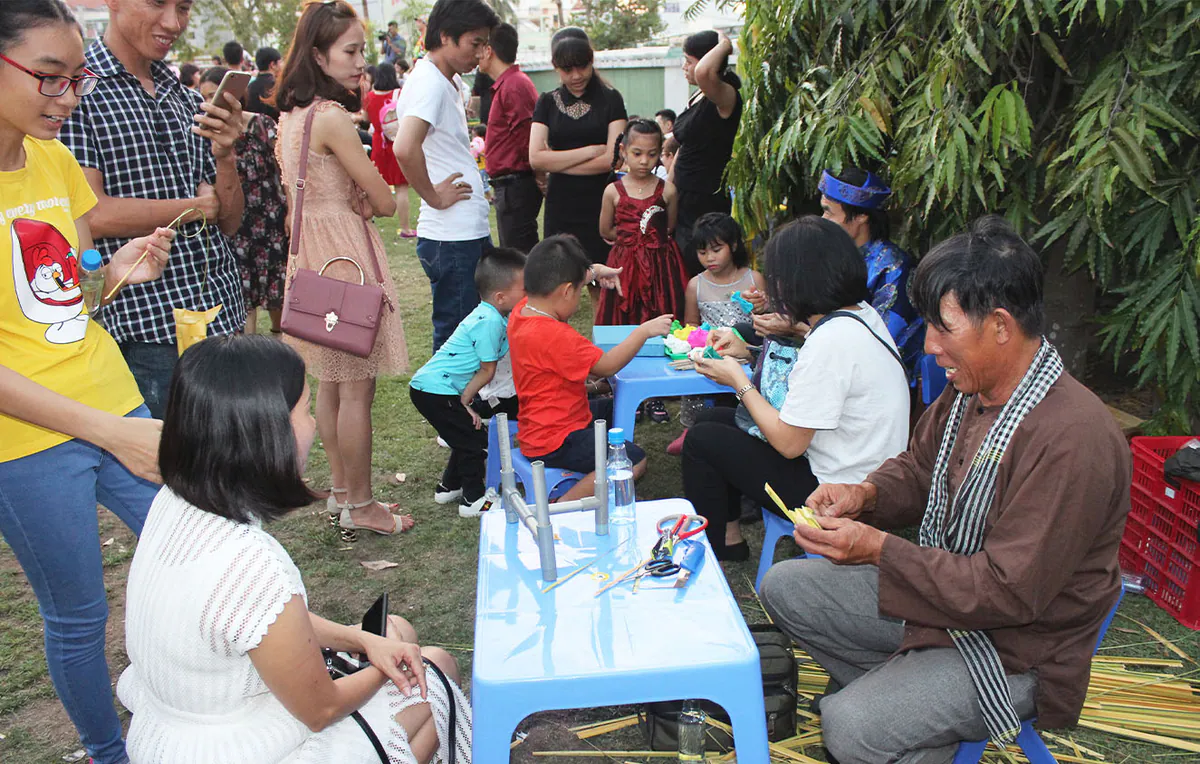 Gian hàng nghệ nhân làm cào cào bằng lá dừa thu hút đông đảo phụ huynh và các bé ngồi xem trải nghiệm nghệ thuật truyền thống tại sự kiện.