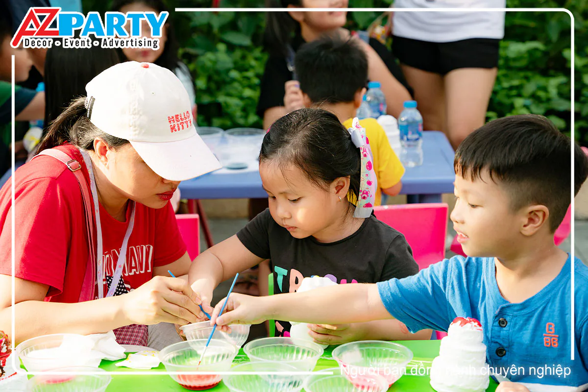 Hai bé thiếu nhi cùng mẹ vui vẻ trải nghiệm hoạt động tô tượng thạch cao đầy màu sắc.