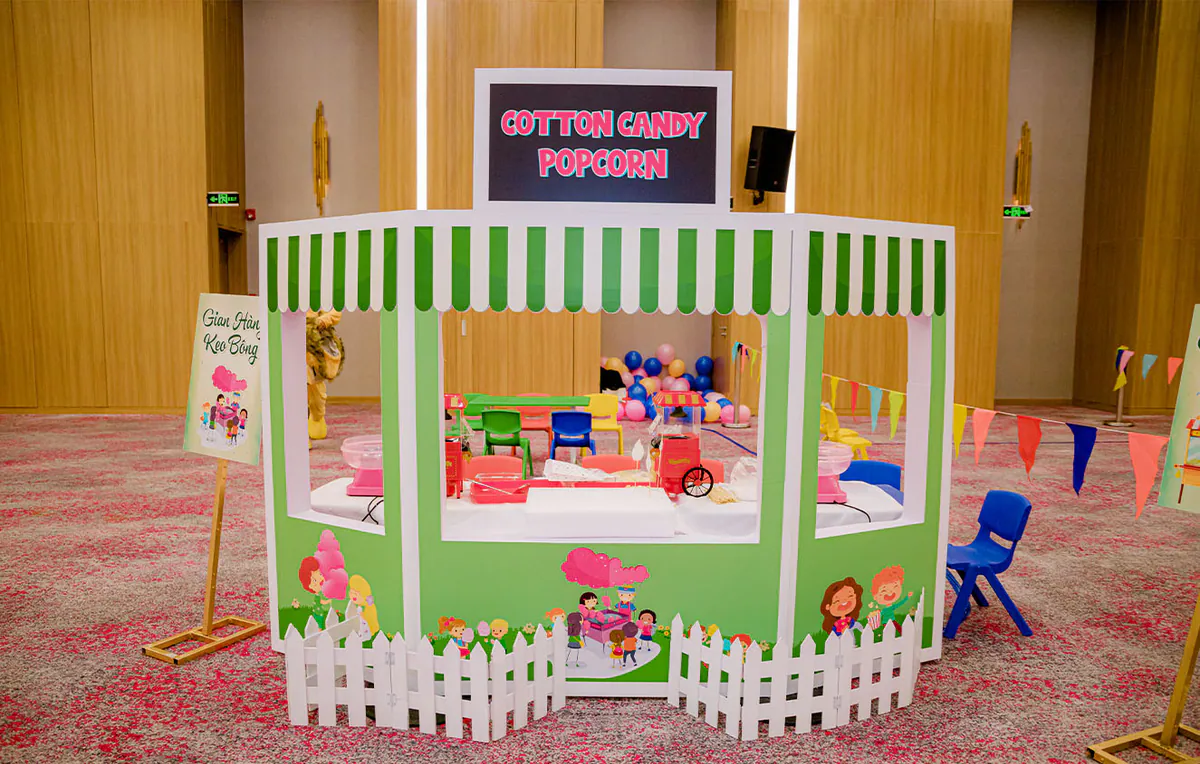 Gian hàng phục vụ Kẹo bông (Cotton Candy) và Bắp rang bơ (Popcorn) được thiết kế hình ngôi nhà màu xanh lá dễ thương có hàng rào trắng bao quanh.