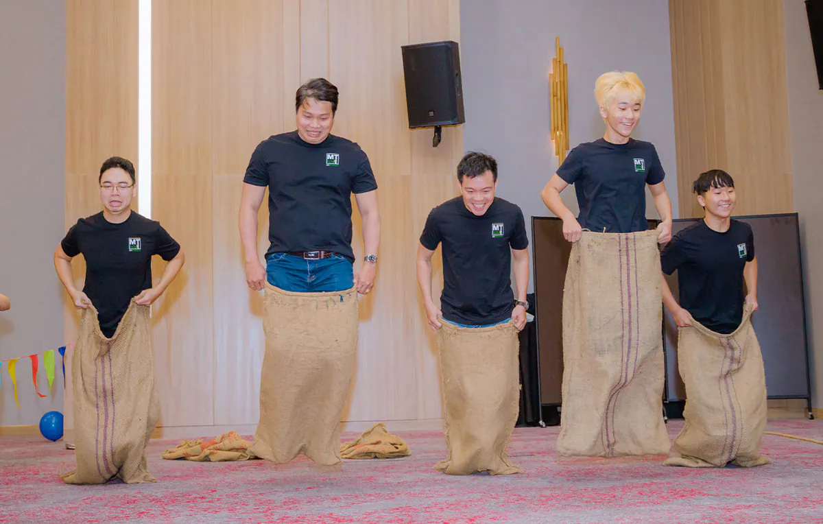 Các ông bố trẻ trong chiếc áo thun đen đồng phục đang nhảy bao bố kịch tính và hài hước trong phần thi đấu của ngày hội gia đình.