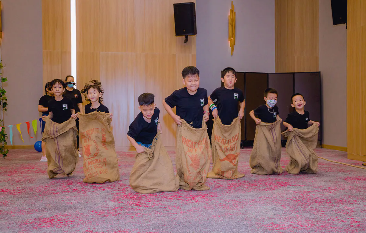 Các bé trai bé gái hào hứng và đầy quyết tâm trong phần thi nhảy bao bố dành cho thiếu nhi tại sảnh sự kiện.