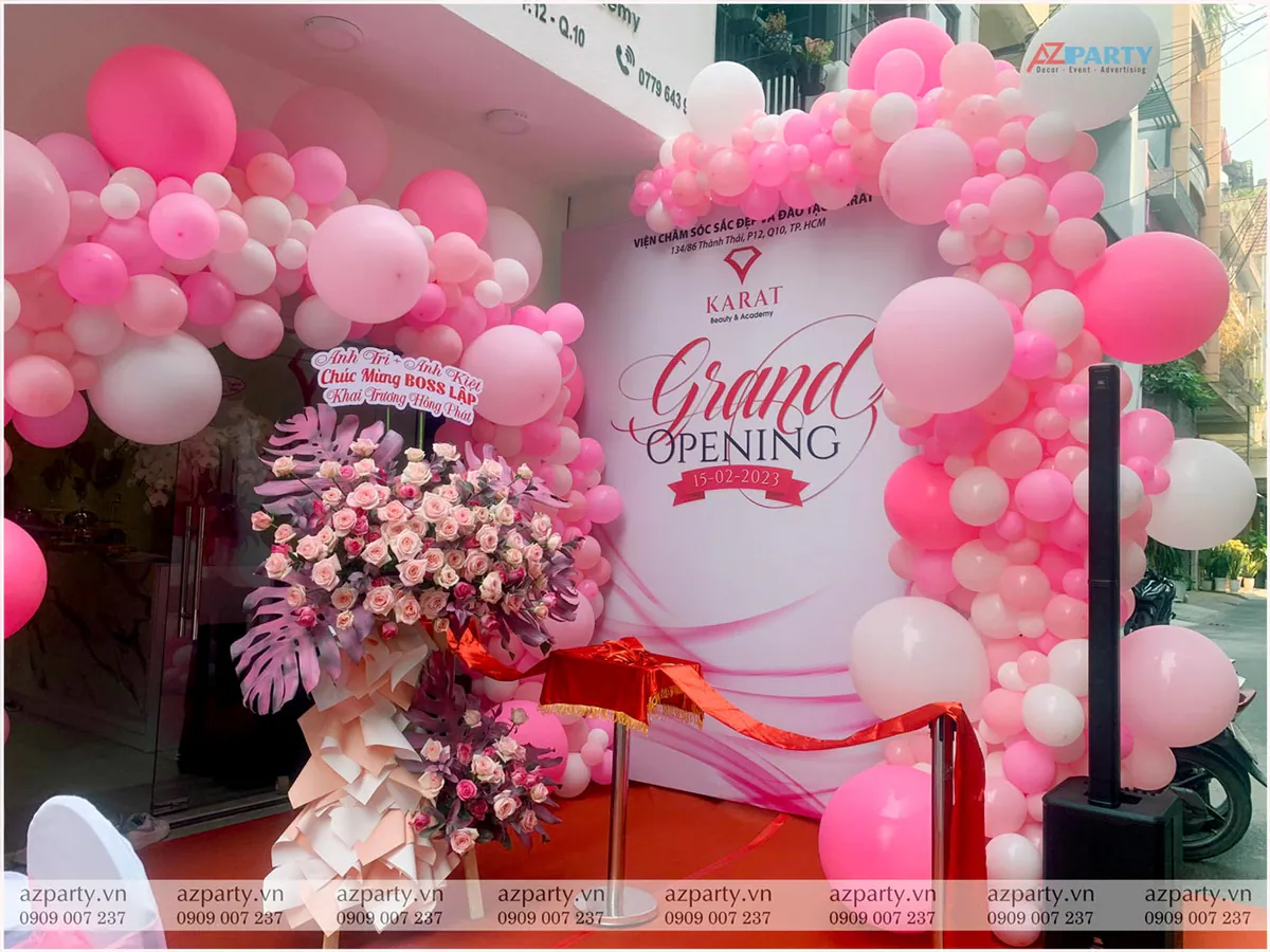 Backdrop Grand Opening lễ khai trương Karat Beauty & Academy trang trí bong bóng và hoa tươi.