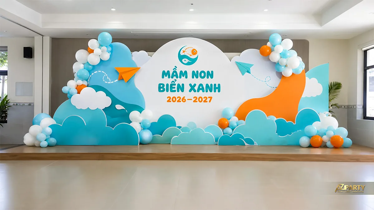 Sân khấu khai giảng mầm non Biển Xanh với mây xanh, máy bay giấy và bóng trắng cam