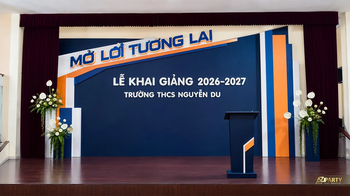 Sân khấu THCS Nguyễn Du màu xanh cam với thông điệp Mở lối tương lai và hoa hai bên