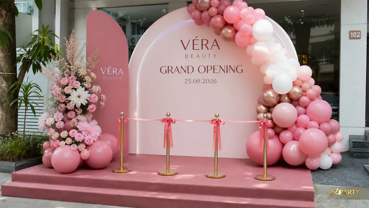 Sân khấu Véra Beauty màu hồng với cụm bóng pastel và dải băng khai trương