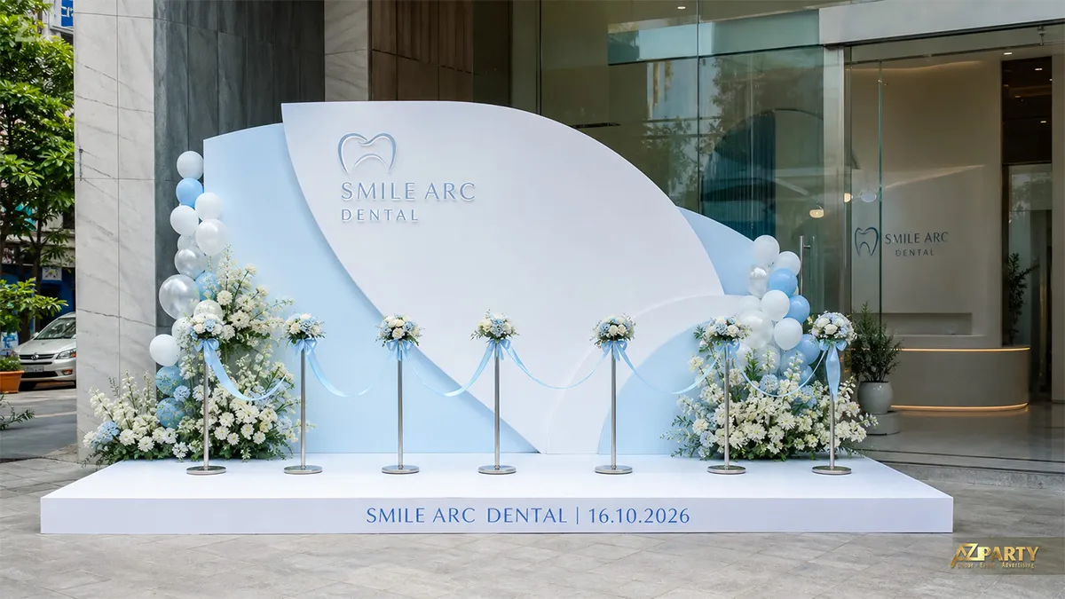 Sân khấu Smile Arc Dental trắng xanh với hoa trắng và dải băng xanh nhạt