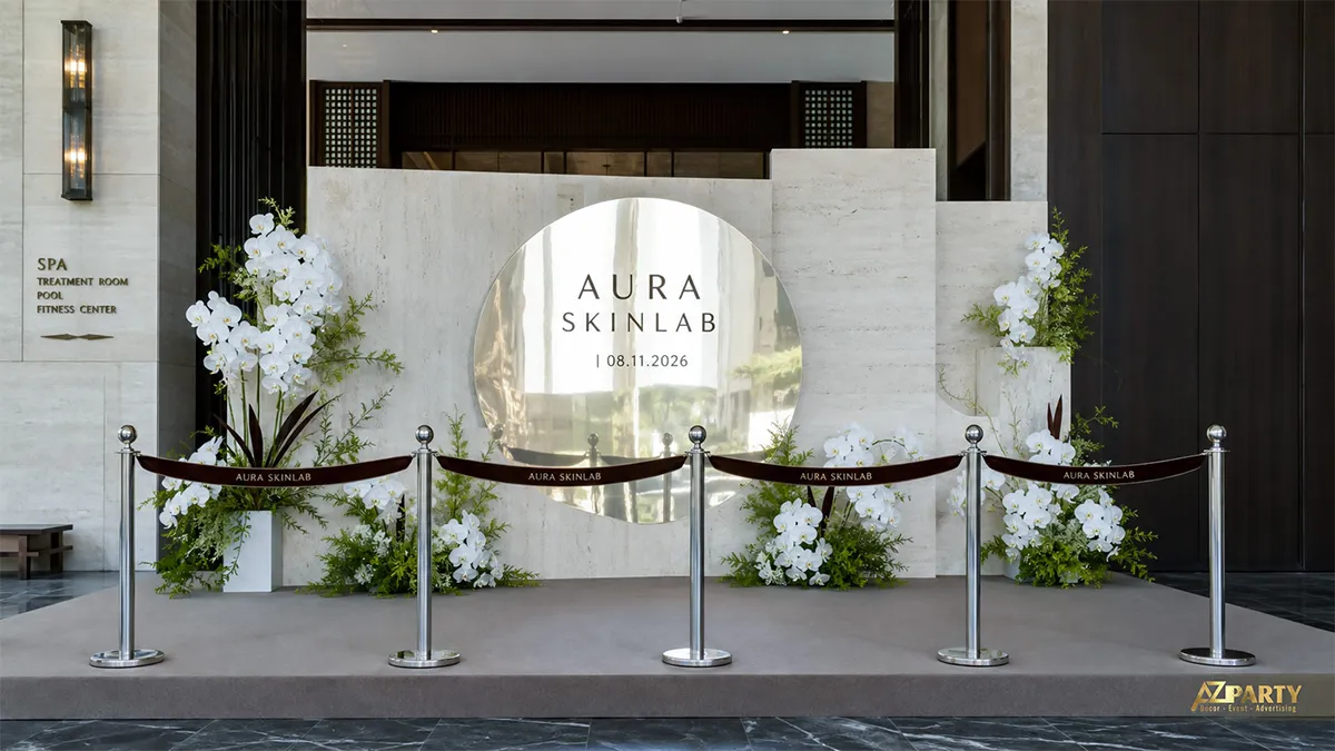 Sân khấu Aura Skinlab vân đá với gương tròn trung tâm và các cụm lan trắng