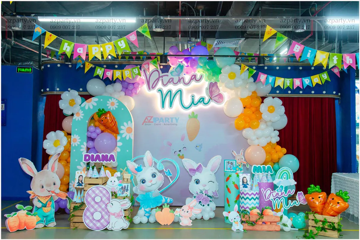 Trang trí sân khấu sinh nhật bé gái Diana và Mia với backdrop in hình thỏ Bunny dễ thương, các mô hình standee thỏ hồng, số 8 và cà rốt ngộ nghĩnh.