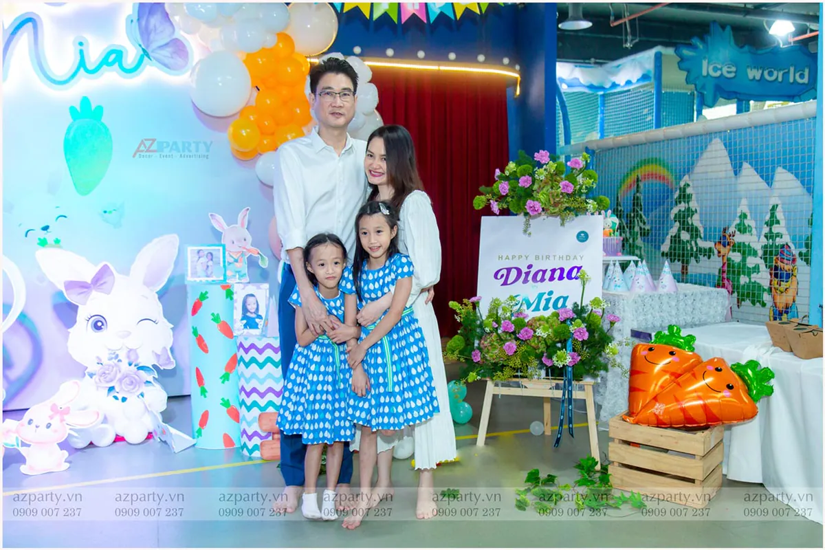 Cả gia đình bốn người chụp hình chung lưu niệm trước sân khấu trang trí thỏ Bunny và cà rốt đáng yêu của tiệc sinh nhật.
