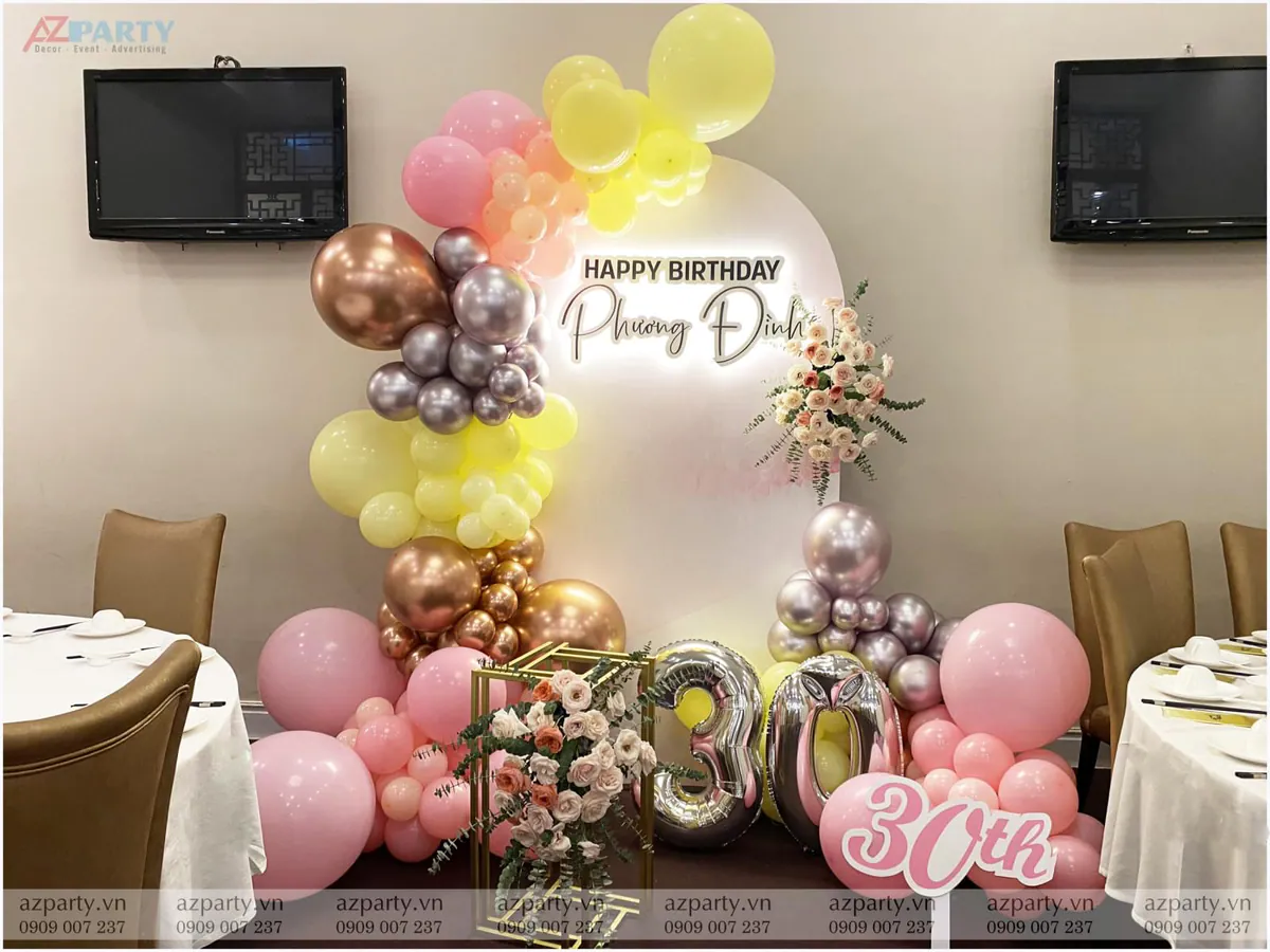 Trang trí tiệc sinh nhật lần thứ 30 của Phương Đình với backdrop tròn tông màu pastel ngọt ngào, bong bóng màu hồng, vàng nhạt, bạc và rose gold sang trọng cùng hoa tươi và bong bóng số 30 nổi bật.