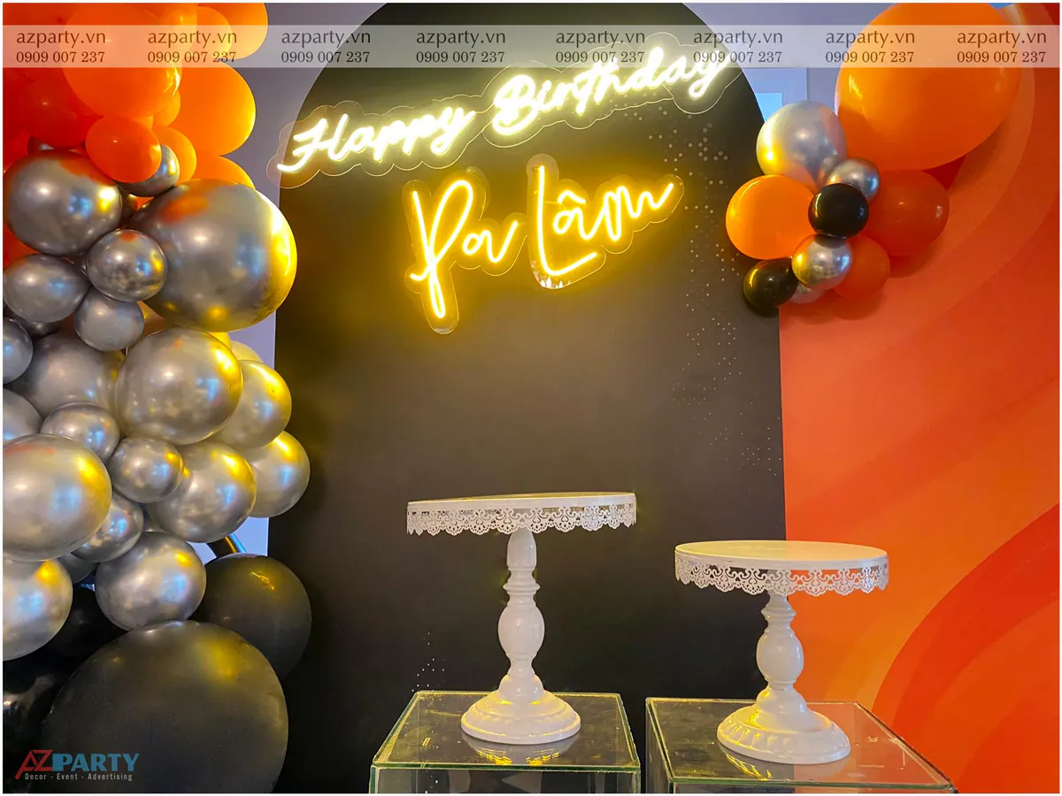 Cận cảnh chữ đèn neon vàng Happy Birthday Ba Lâm tỏa sáng rực rỡ phía trên hai đôn gallery mica trong suốt đặt đế bánh ren trắng cổ điển.