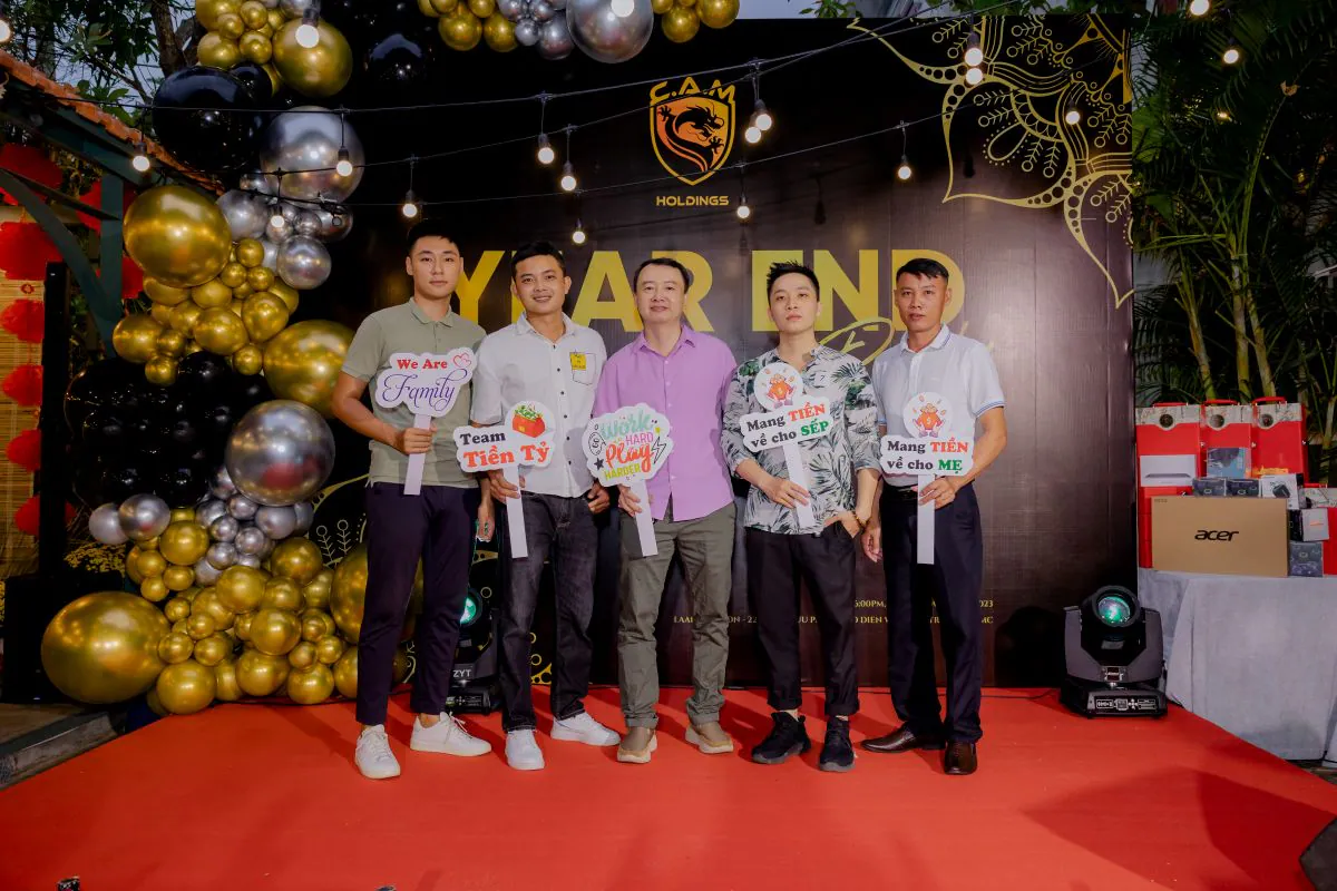 Nhóm 5 nhân viên nam C.A.M Holdings check-in trên sân khấu với các hashtag vui nhộn tại tiệc tất niên