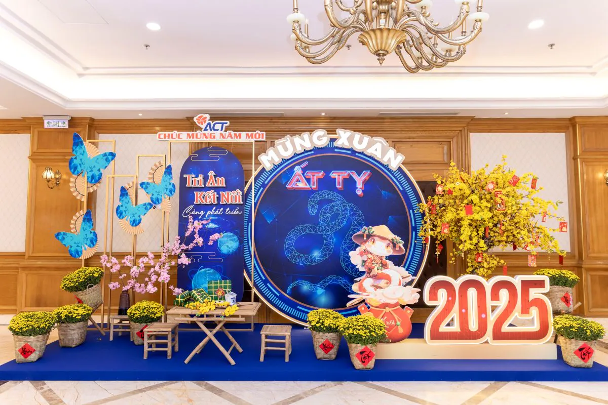 Khu vực tiểu cảnh photobooth check-in Year End Party ACT 2024 được trang trí đậm chất Tết Việt với hoa mai vàng, hoa cúc mâm xôi và mô hình số 2025 nổi bật.