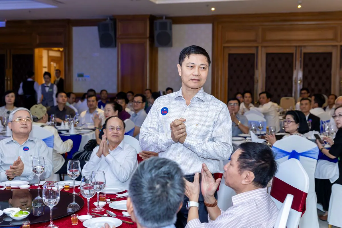Một khách mời đứng dậy giới thiệu bản thân và chào hỏi mọi người tại bàn tiệc trong tràng pháo tay giòn giã.