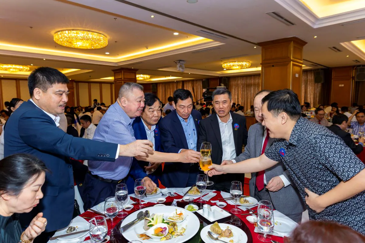 Các khách mời nam vui vẻ đứng lên cụng ly chúc mừng nhau tại bàn tiệc trong hội trường tiệc tất niên ACT.