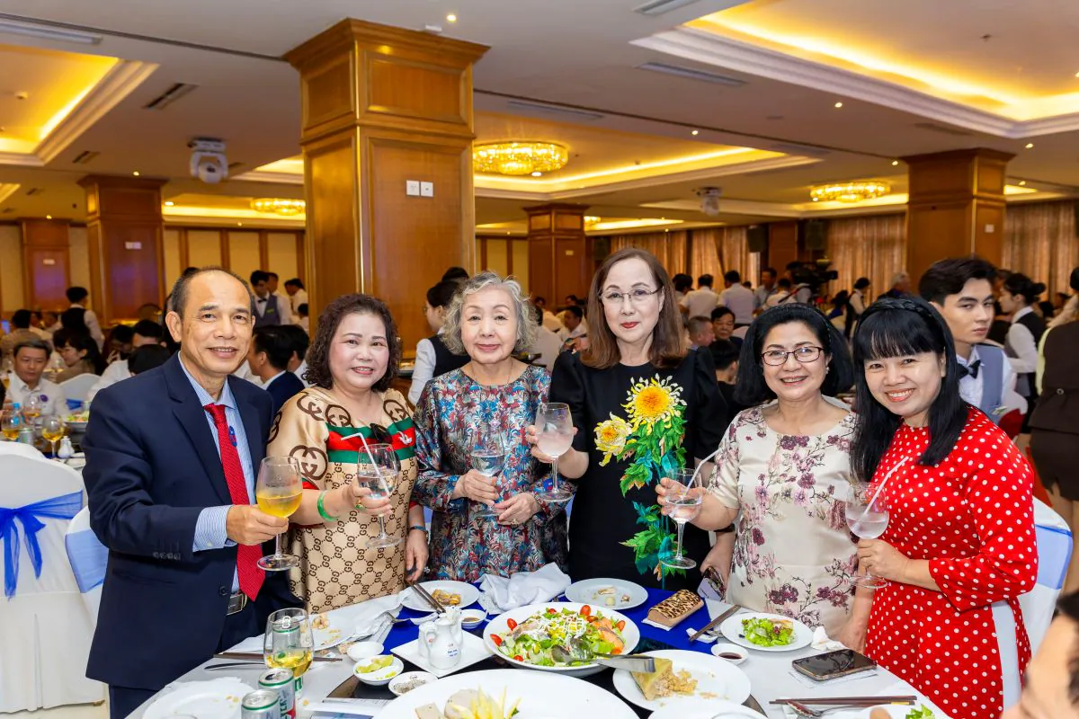 Nhóm khách mời nữ trung niên cùng đại biểu nam rạng rỡ nâng ly chúc mừng tại bàn tiệc tất niên ACT.