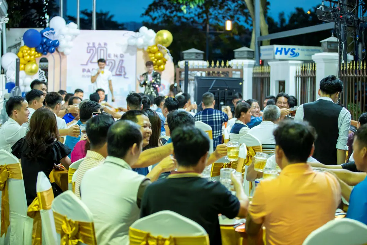 Không khí tưng bừng tại các bàn tiệc ngoài trời của sự kiện tất niên HVS Group, nơi các thành viên nâng ly bia chúc mừng một năm thành công.