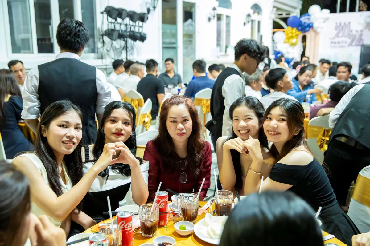 Nhóm nhân viên nữ của HVS Group vui vẻ tạo dáng chụp ảnh tại bàn tiệc trong sự kiện Year End Party ngoài trời được trang trí trang nhã.