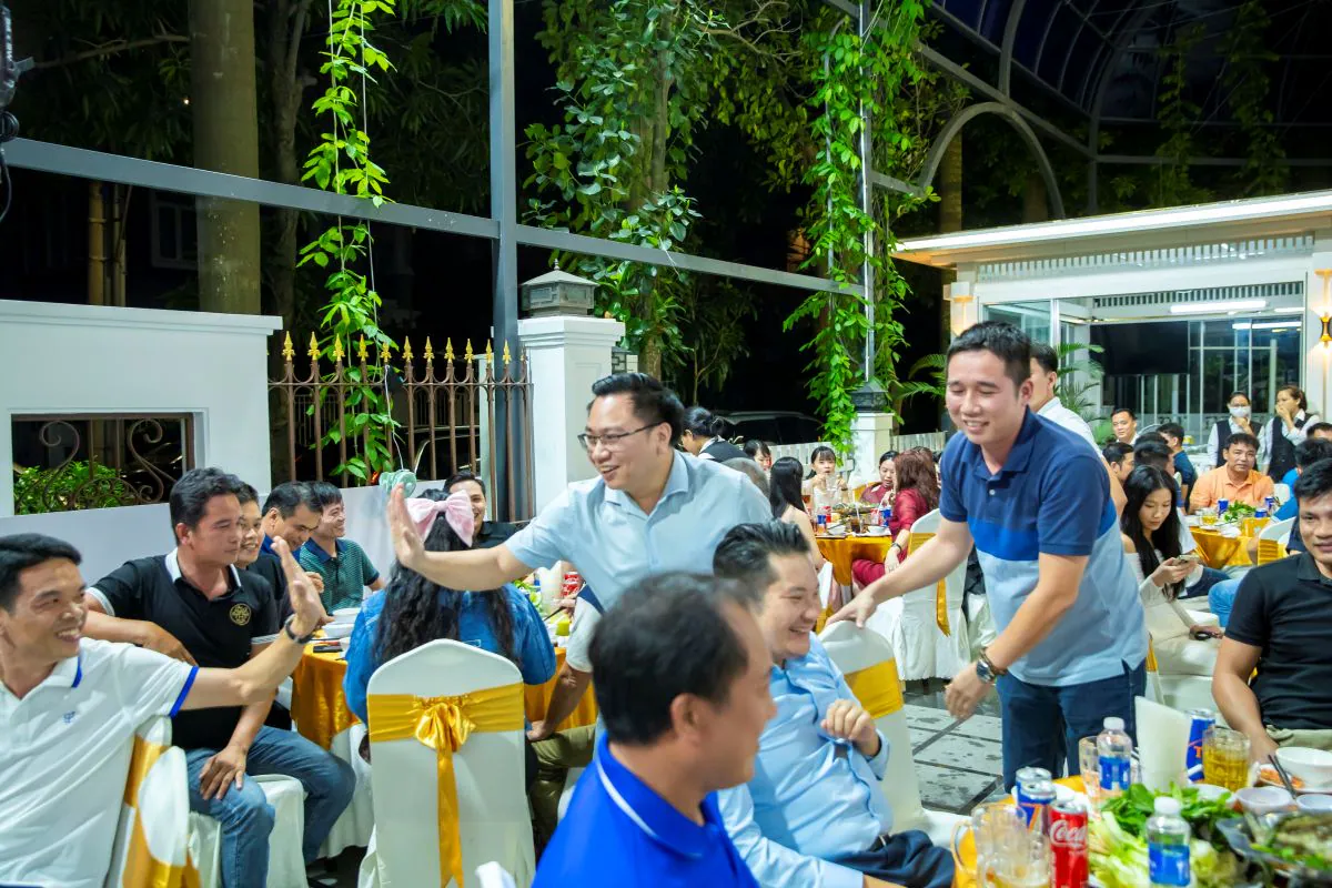 Các thành viên HVS Group tương tác vui vẻ, đập tay chúc mừng đầy hứng khởi tại không gian tiệc ngoài trời.